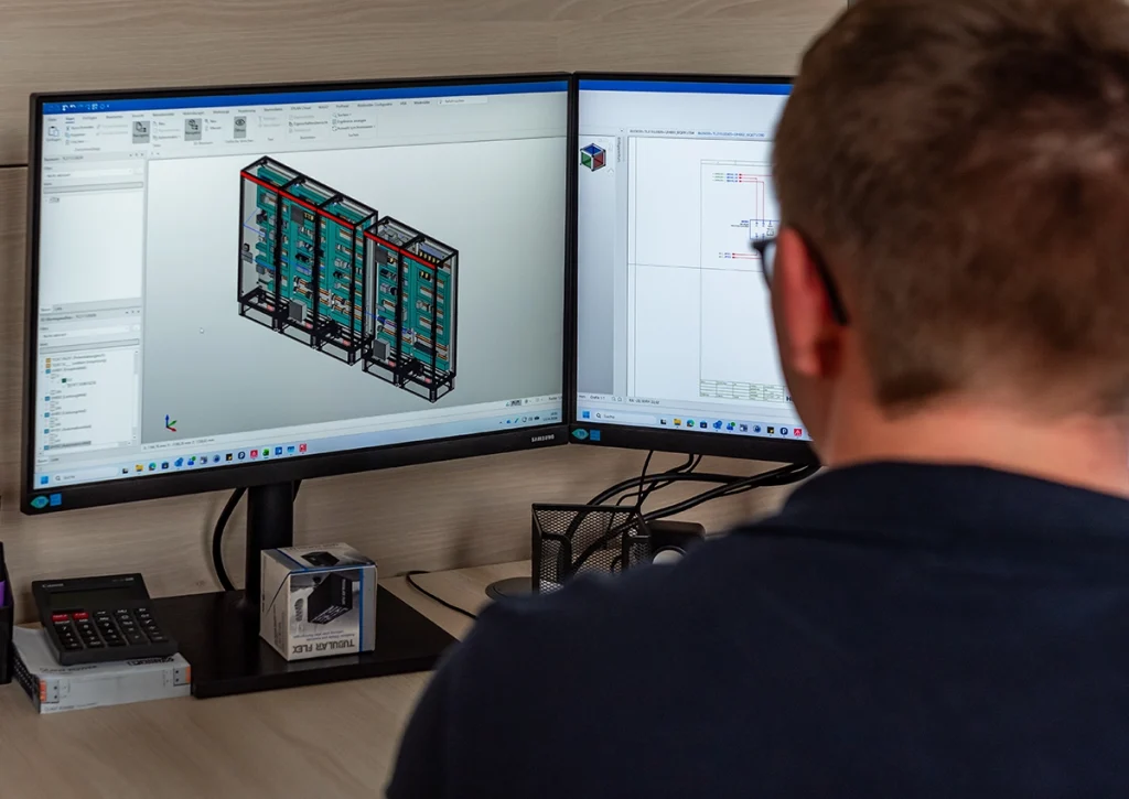 Mitarbeiter erstellt am Computer technische Konstrukions- und Schaltpläne für industrielle Schaltanlagen.