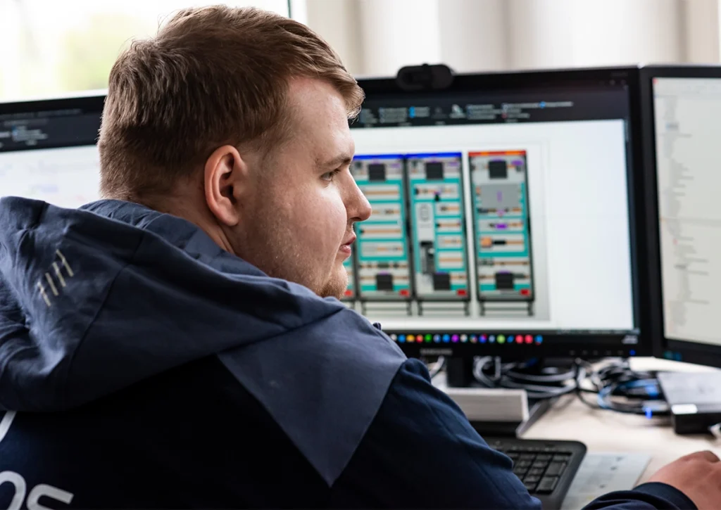 Projektmanager analysiert technische Unterlagen und Plantafeln am Computerarbeitsplatz.